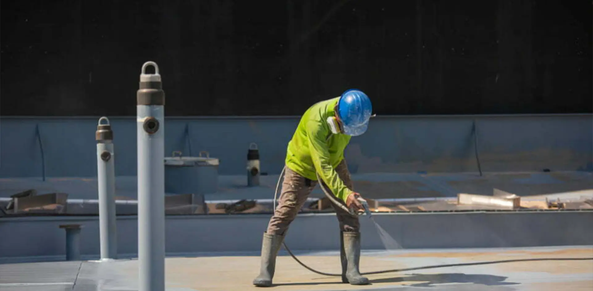 A roofer performing patch repairs and applying protective sealants on a roof surface
